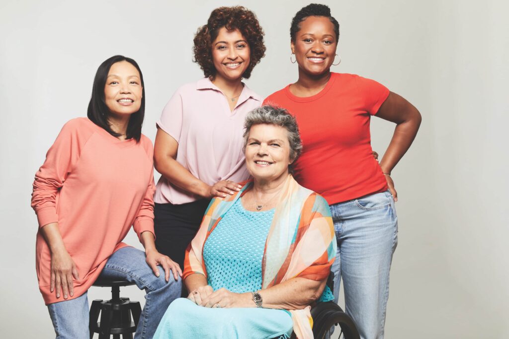 Four women representing diverse ages, ethnicities, and body types stand together, smiling and posing side‑by‑side.