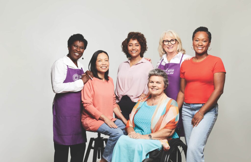 Two Look Good Feel Better volunteers stand while four workshop participants – two seated and two standing – pose together smiling.