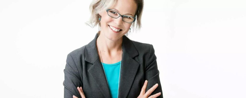 Dr Linda Carlson wearing an aqua blouse under a charcoal blazer.