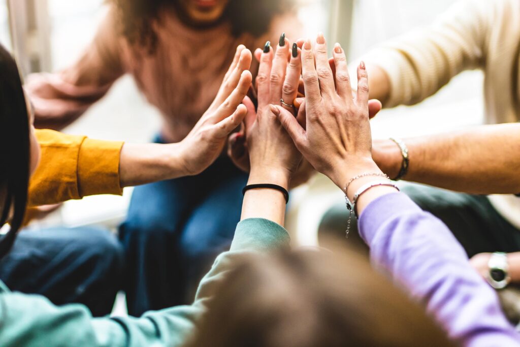 A group of people high fiving each other in a circle.