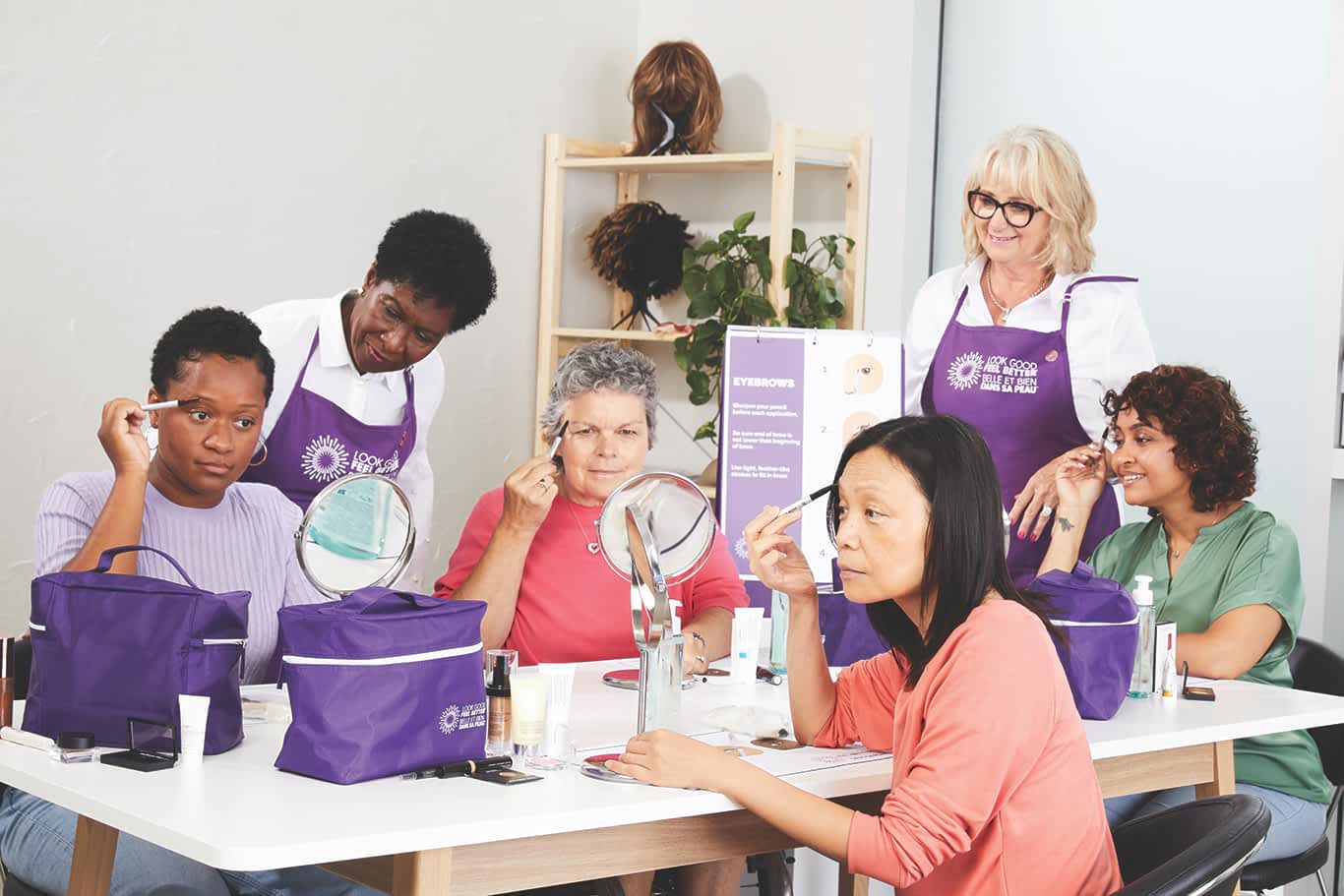 Plusieurs femmes se maquillent lors d'un atelier Belle et bien dans sa peau, aidées par des bénévoles.