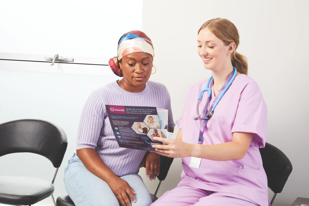 A woman wearing a head scarf getting shown a brochue by a nurse in purple scrubs.