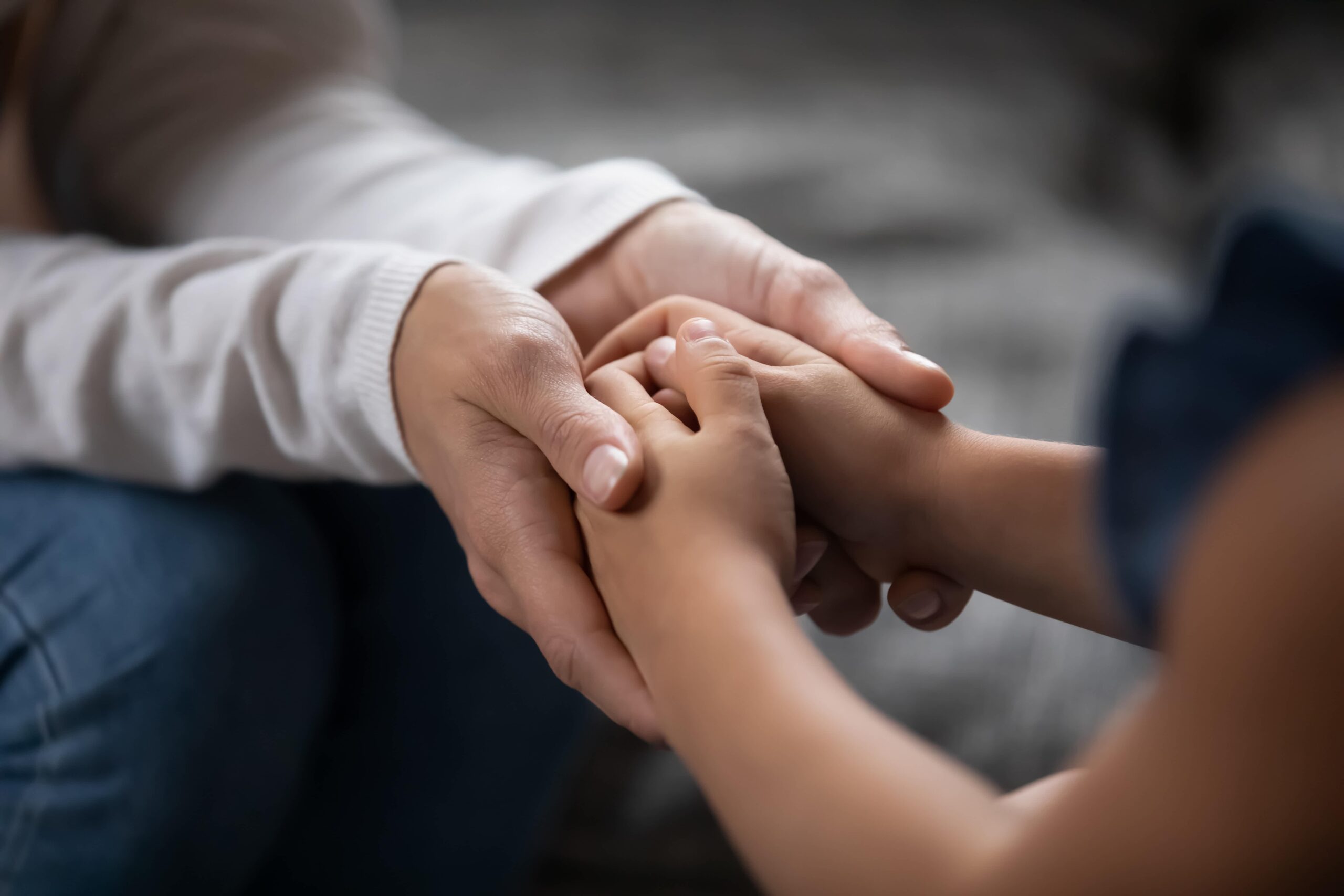 A close-up of a parent holding their young child's hand.