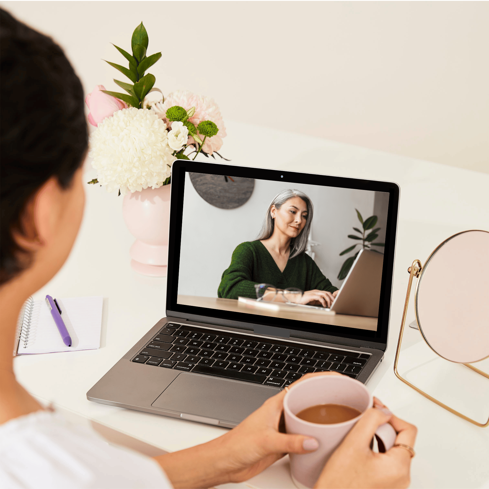 Over-the-shoulder view of a woman at a desk looking at a back to work workshop on a laptop.