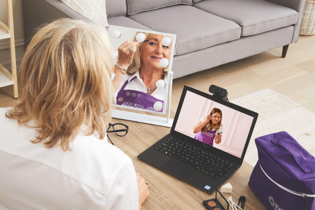 Une bénévole Belle et bien dans sa peau regarde une vidéo de formation sur son ordinateur portable tout en se dessinant les sourcils.