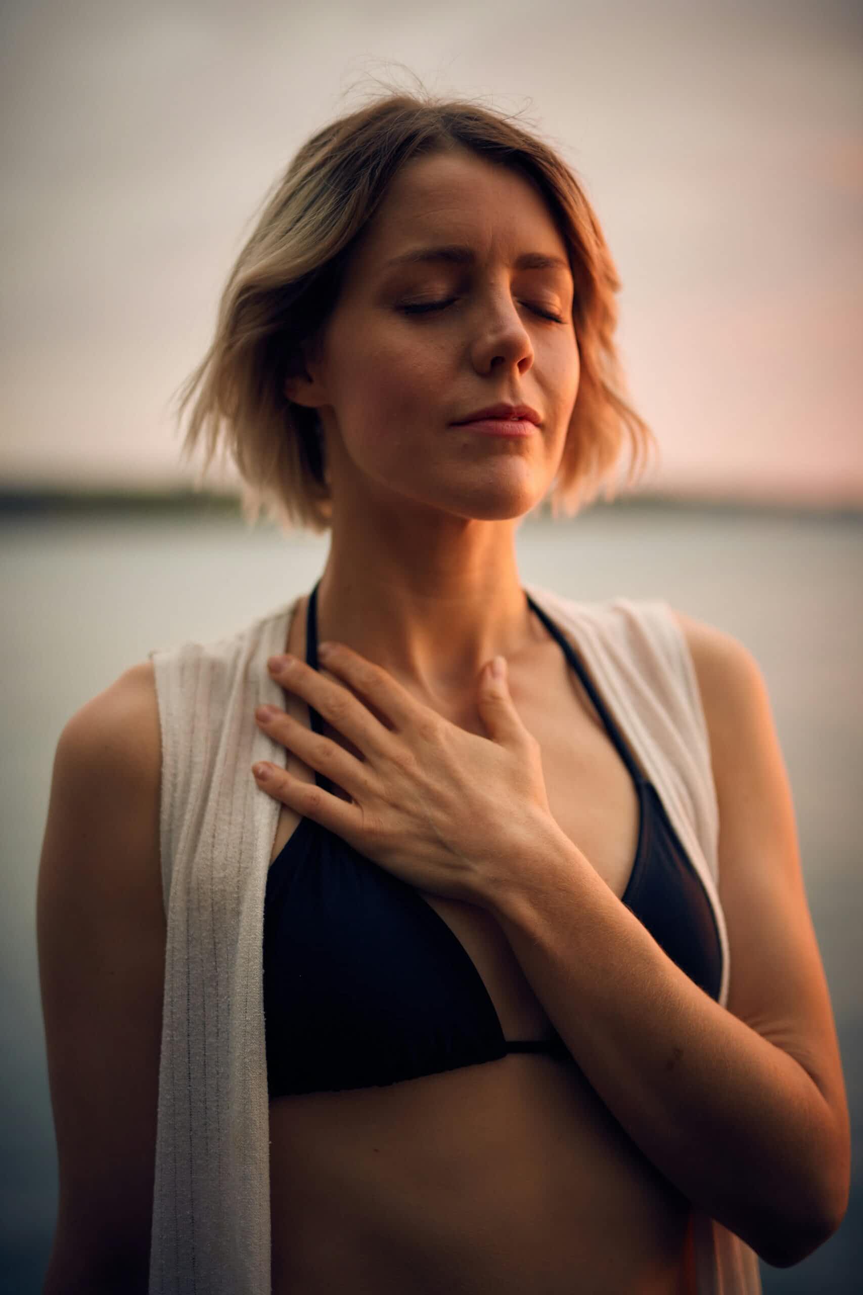 Femme respirant profondément, la main posée sur la poitrine.