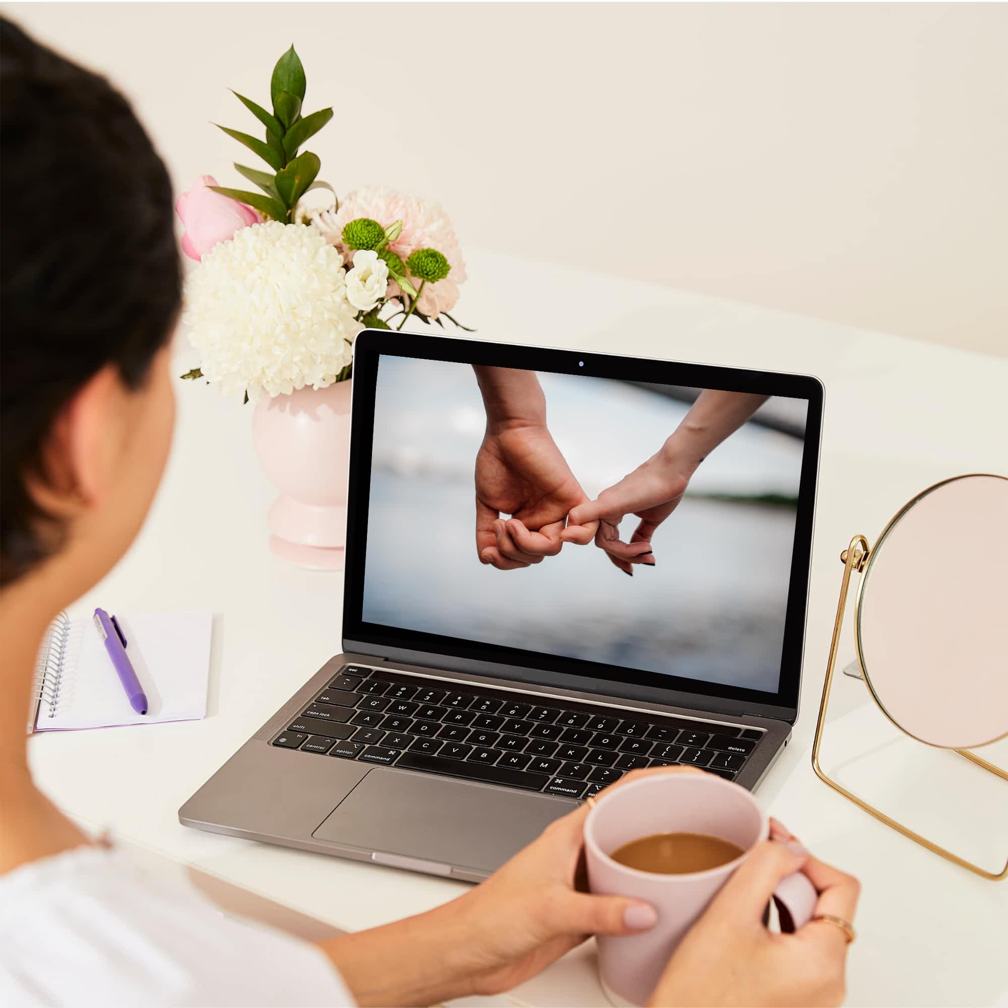 On overhead shot of a woman watching an online Sexual Wellbeing workshop on her laptop.