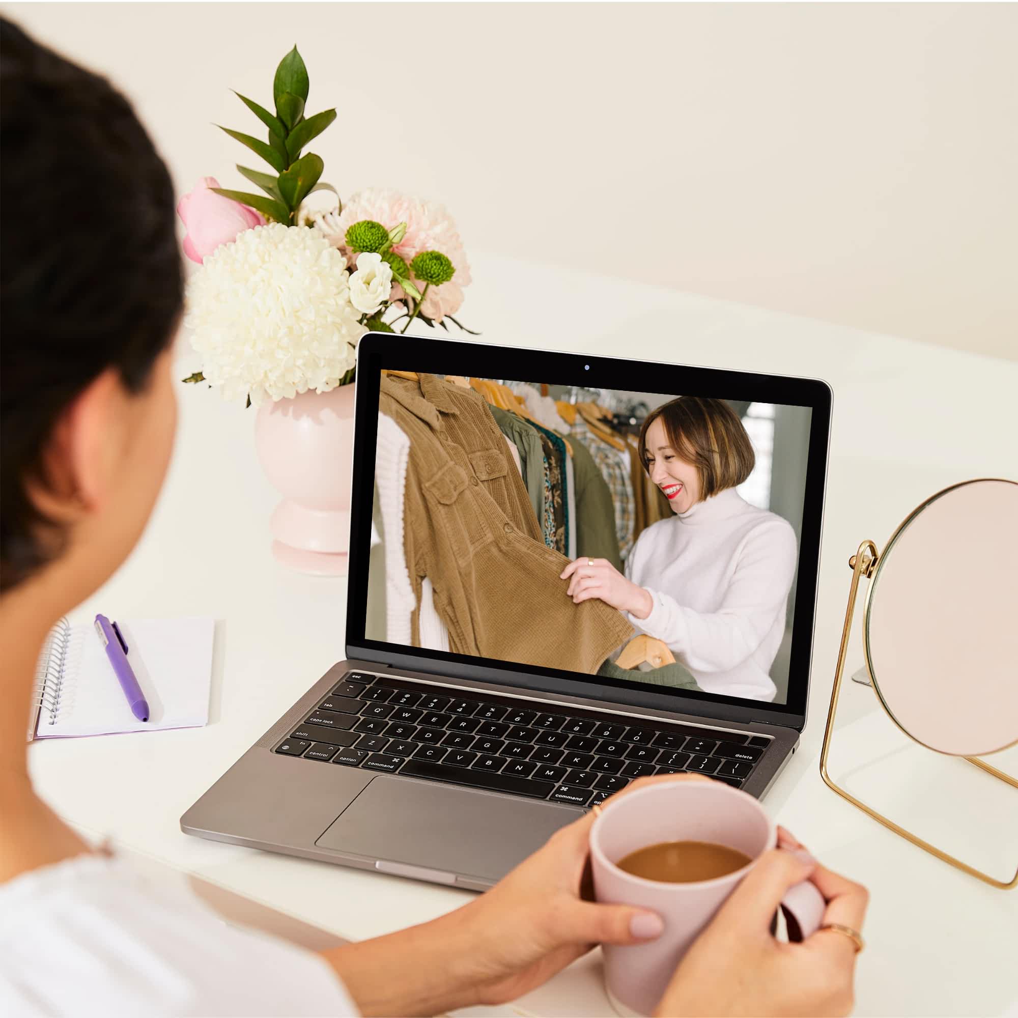 An overhead shot of a woman watching a Style & Clothing Workshop on a laptop.
